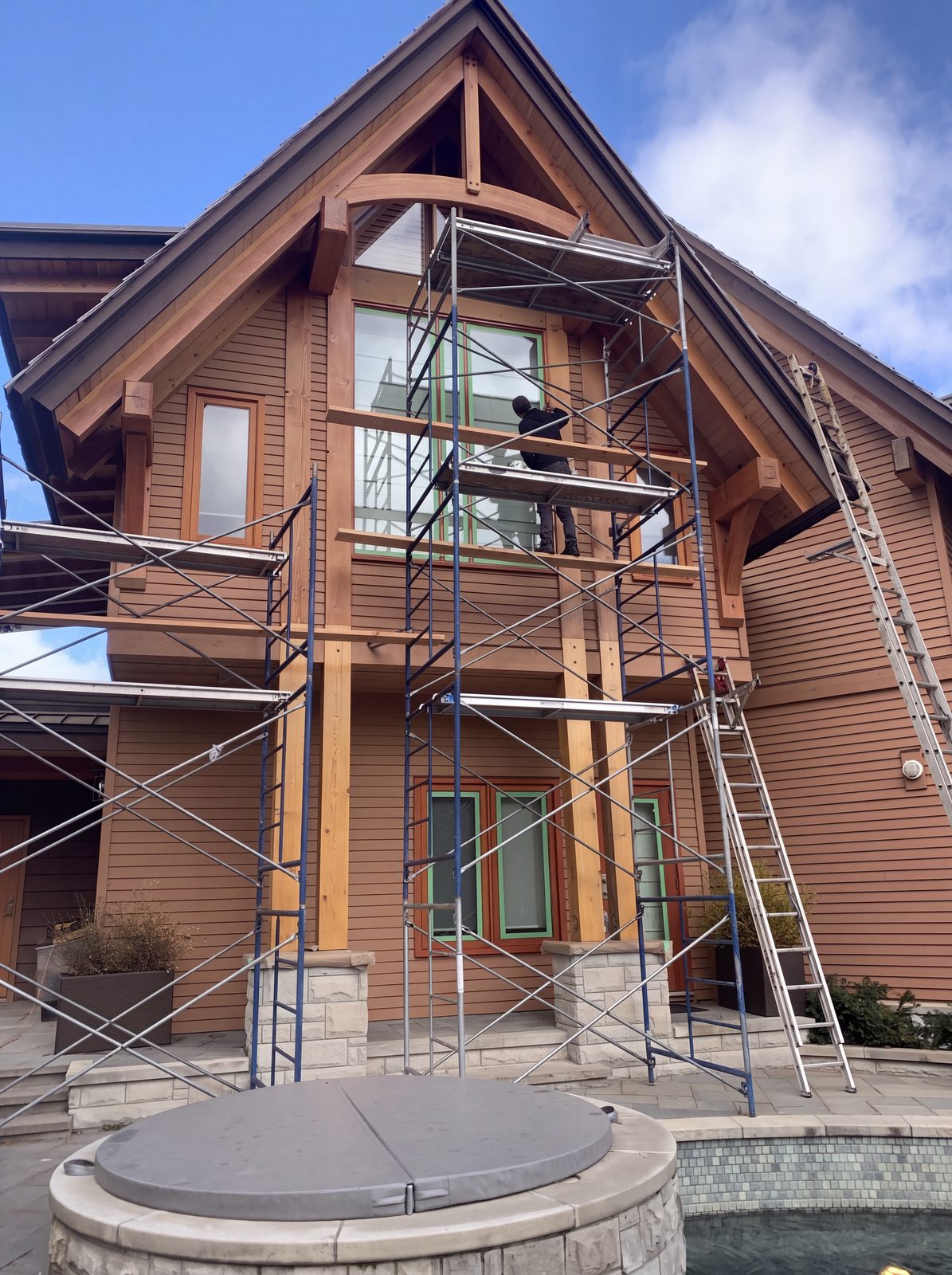 Log home sanding and staining in Whistler BC - crew working from scaffold on a timber-frame home