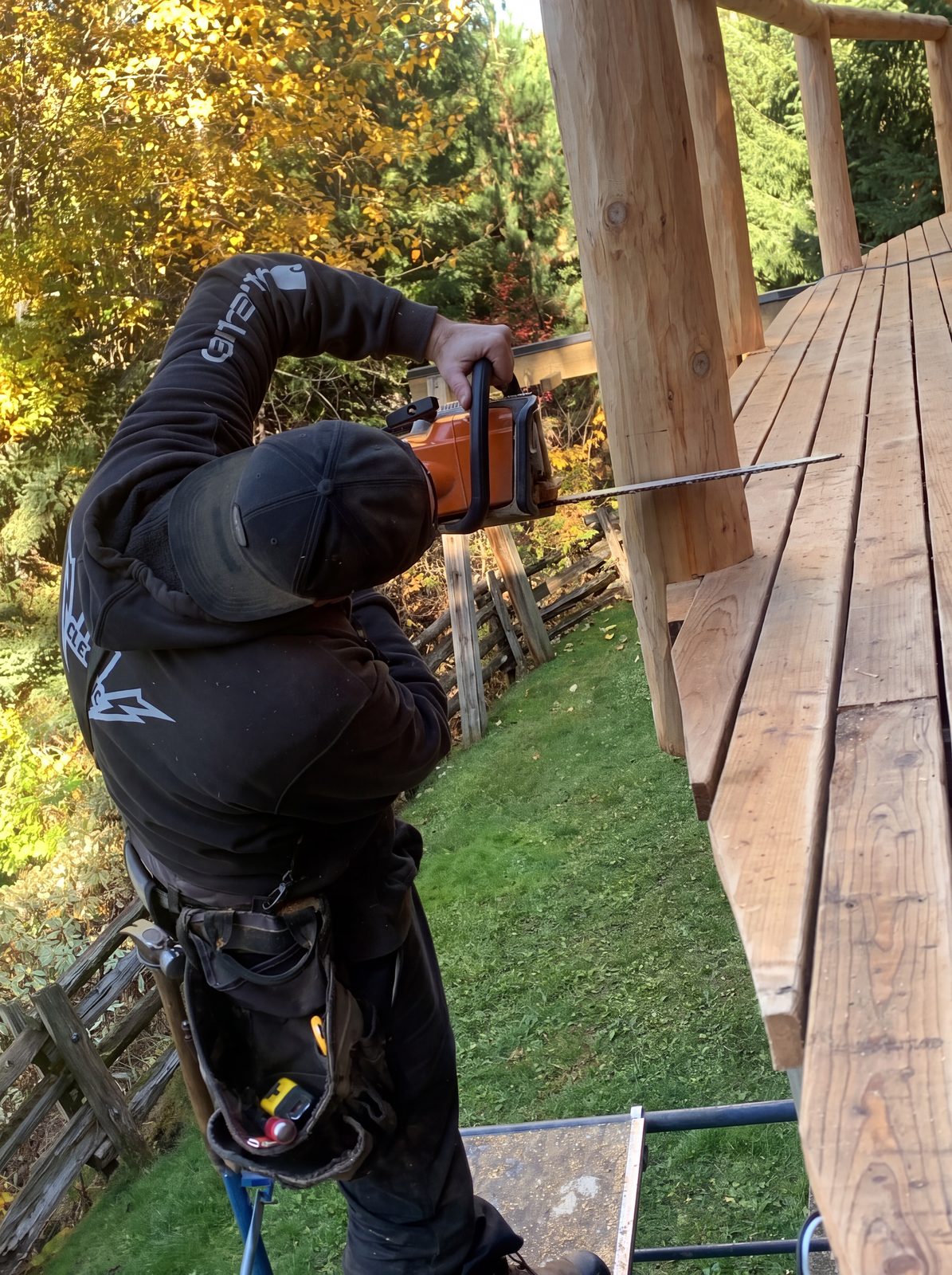 Duckwood cutting a new log railing to fit on a Sea to Sky log home